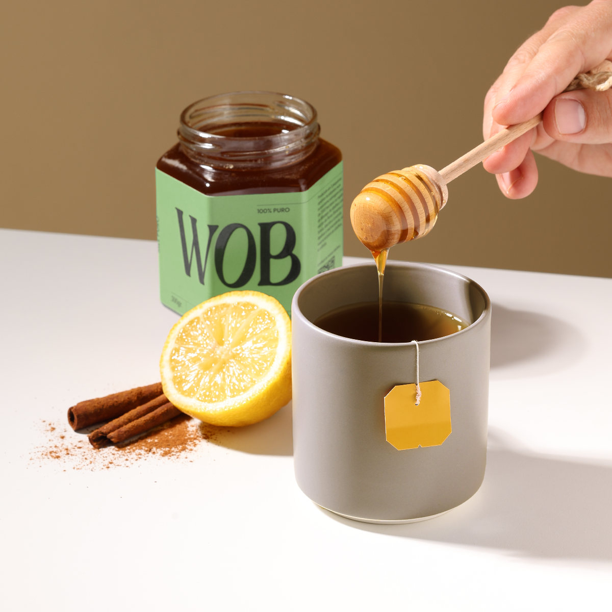 Mão a verter mel de urze World of Bees num chá quente e aromático